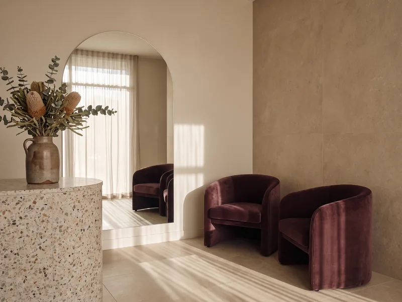 A quiet clinic reception with an arched mirror and afternoon light